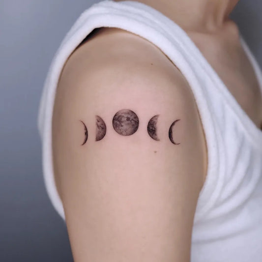 Small Black and Grey Moon Phases Tattoo on Women Shoulder by @uno.tat