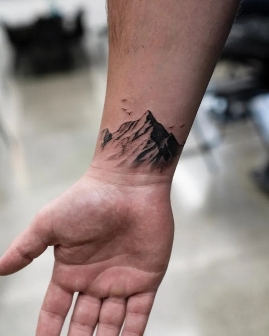 Small Black and Grey Mountain and Birds Tattoo on Men Wrist by @coenmitchell