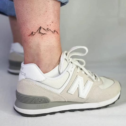 Small Black and Grey Mountain and Birds Tattoo on Women Ankle by @_nono_tattoo