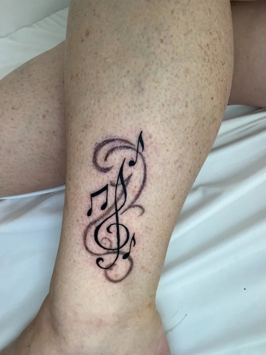 Small Black and Grey Musical Notes Tattoo on Women Leg by @peace_inkart