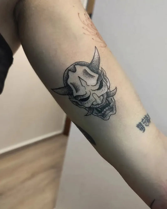 Small Black and Grey Oni Mask on Women Arm Tattoo by @nine.tailedtattoo