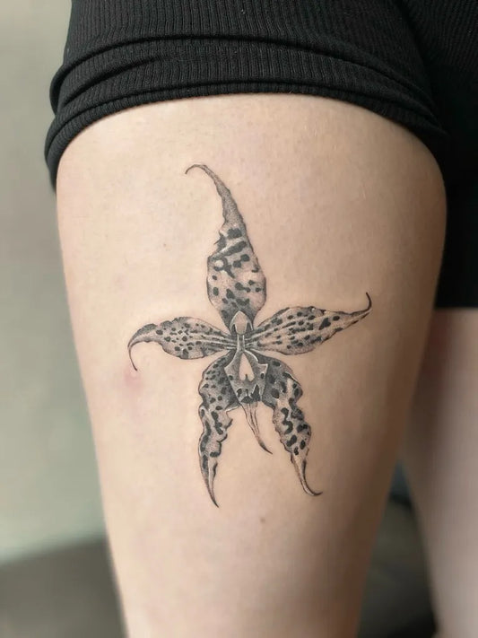 Small Black and Grey Orchid Tattoo on Women Thigh by @badshottattoo