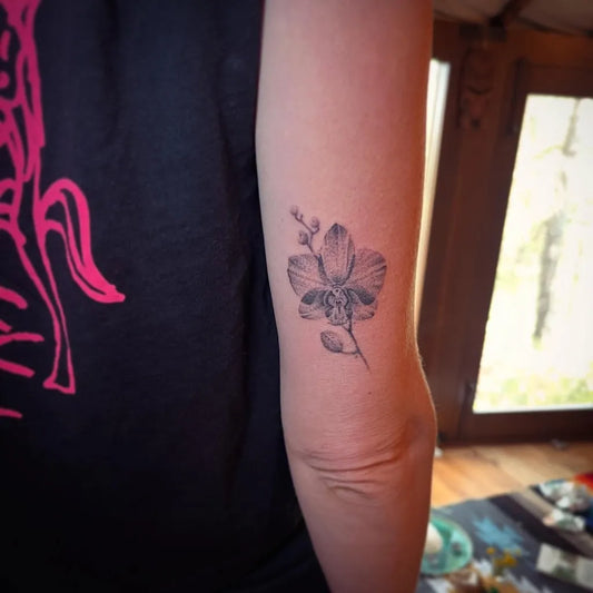 Small Black and Grey Orchid Tattoo on Women Upper Arm by @earthlink.jim