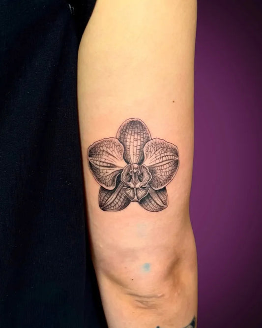 Small Black and Grey Orchid Tattoo on Women Upper Arm by @toozentattoos