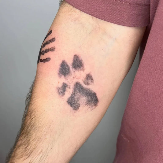 Small Black and Grey Paw Print Tattoo on Men Arm by @alex.niamh.tattoos