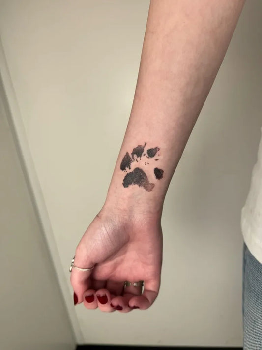 Small Black and Grey Paw Print Tattoo on Women Wrist by @miss_skeletor_tattoo