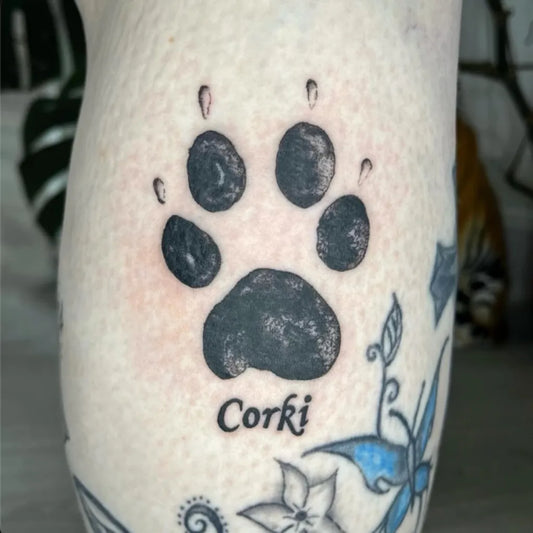 Small Black and Grey Paw Print and Corgi Tattoo on Women Leg by @moonstonetattoostudio