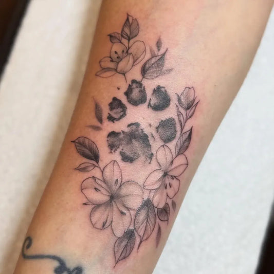 Small Black and Grey Paw Print and Flowers Tattoo on Women Arm by @mamatried.tattoosmith