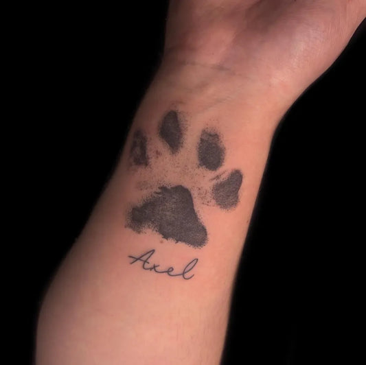 Small Black and Grey Paw Print and Name Tattoo on Men Wrist by @abigailblacktatts