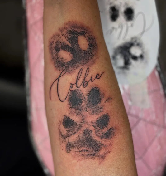 Small Black and Grey Paw Print and Name Tattoo on Women Arm by @_camsee_
