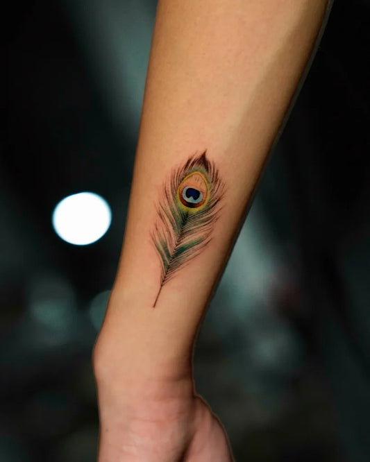 Small Black and Grey Peacock Feather Tattoo on Women Forearm by @jinkblack_tattoo