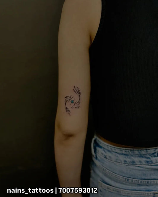 Small Black and Grey Pisces Tattoo on Women Arm by @nains_tattoos