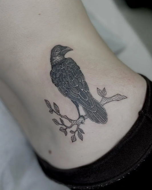Small Black and Grey Raven on Branch on Women Hip Tattoo by @kgw.tattoo