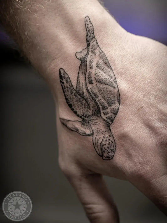 Small Black and Grey Sea Turtle Tattoo on Men Wrist by @zealandtattoo