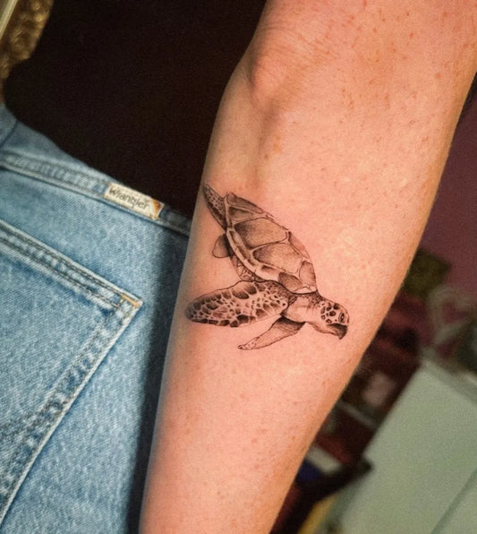 Small Black and Grey Sea Turtle Tattoo on Women Arm by @fridaa.ink