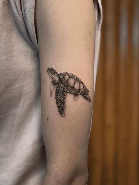 Small Black and Grey Sea Turtle Tattoo on Women Upper Arm by @copper.tatt