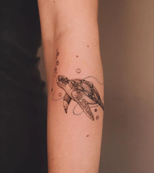 Small Black and Grey Sea Turtle and Bubbles Tattoo on Women Forearm by @gabriela.staneva