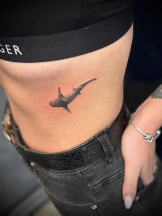 Small Black and Grey Shark on Women Rib Tattoo by @lucy.k.mtattoo