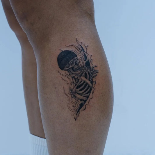 Small Black and Grey Skeleton with Flames Tattoo on Women Leg by @jd.tattooer