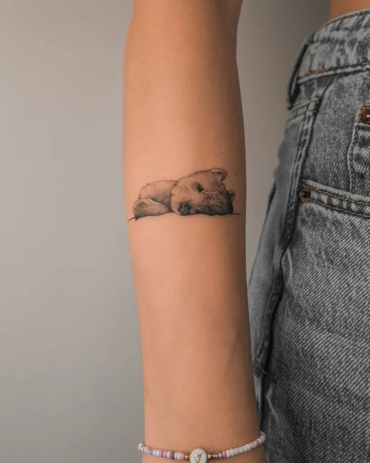 Small Black and Grey Sleeping Dog Tattoo on Women Arm by @lewandowska.ink