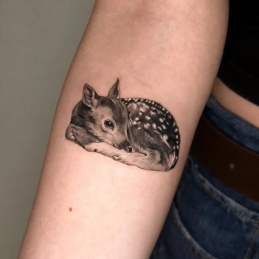 Small Black and Grey Sleeping Fawn Animal Tattoo on Women Arm by @marusia_tattoo