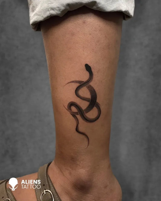 Small Black and Grey Snake Tattoo on Women Leg by @hyderabad_tattoo_company