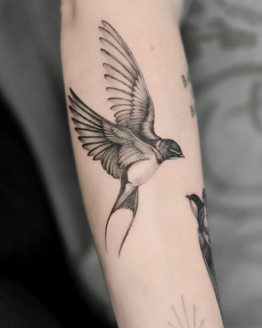 Small Black and Grey Sparrow Tattoo on Women Arm by @krisamber.tattoo