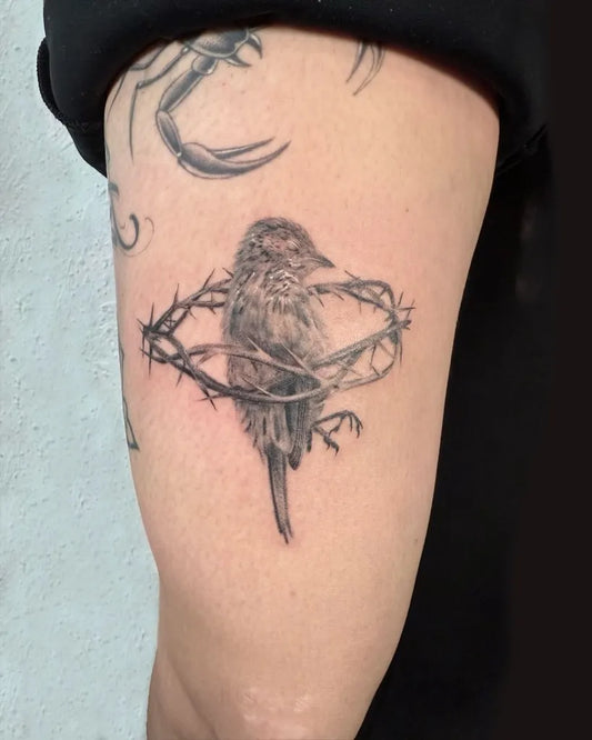 Small Black and Grey Sparrow with Barbed Wire Tattoo on Women Upper Arm by @rickyttattoo