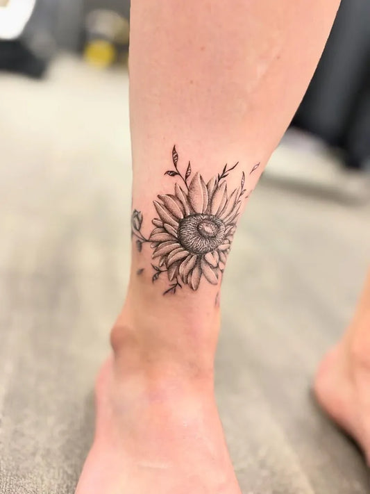 Small Black and Grey Sunflower Tattoo on Women Ankle by @alexforbes_tattoos