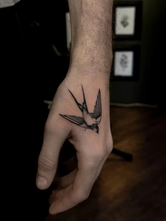 Small Black and Grey Swallow Tattoo on Men Hand by @violatattoos