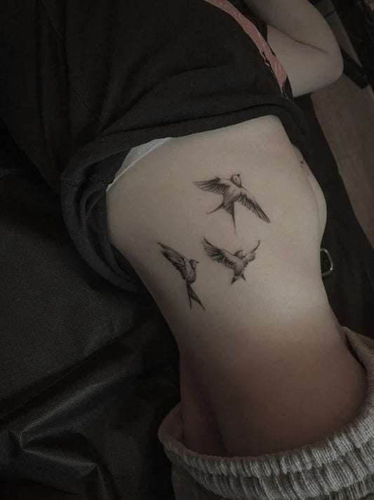 Small Black and Grey Swallows Tattoo on Women Rib by @kahm_tattoo