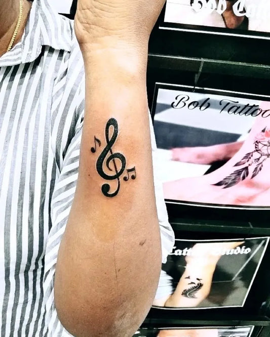Small Black and Grey Treble Clef and Notes Music Tattoo on Women Forearm by @bobtattoostudio_official