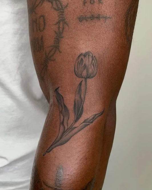 Small Black and Grey Tulip Tattoo on Men Leg by @auraninetyfour
