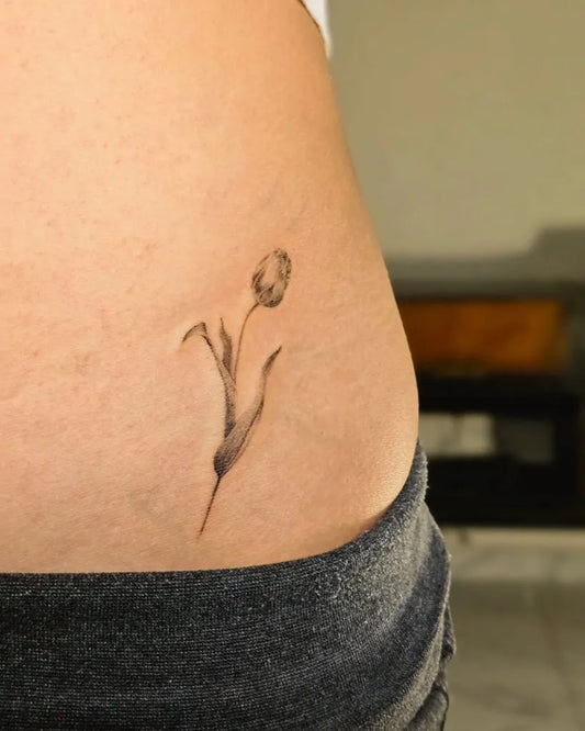 Small Black and Grey Tulip Tattoo on Women Hip by @inactive_tattoo