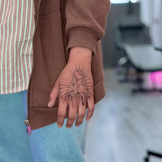 Small Black and Grey Virgin Mary with Sacred Heart Tattoo on Men Hand by @aurelio.tattoos