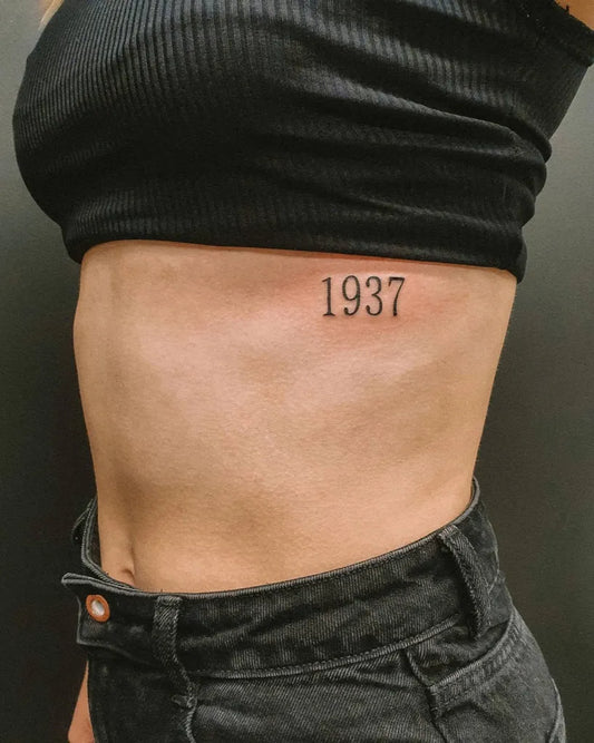 Small Black and Grey Year Number Tattoo on Women Rib by @hybridink.helsinki
