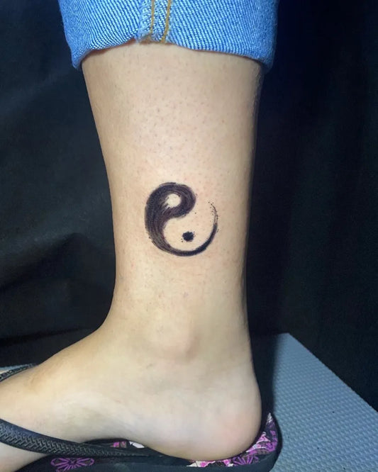 Small Black and Grey Yin Yang Tattoo on Women Ankle by @tah.caires