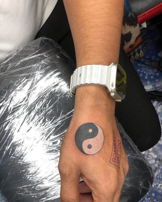 Small Black and White Yin Yang Tattoo on Men Wrist by @bombay.tattoo9