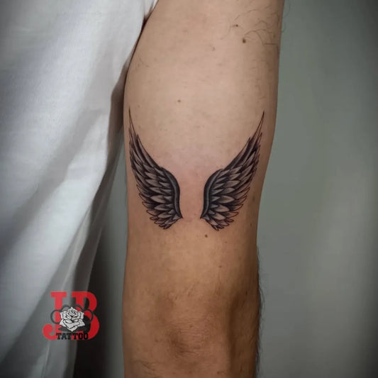 Small Blackwork Angel Wings Tattoo on Men Arm by @joaobrandao.tattoo