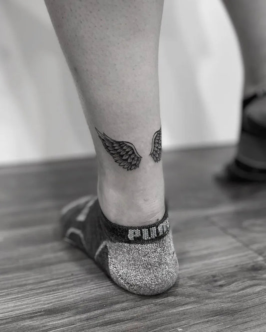 Small Blackwork Angel Wings Tattoo on Women Ankle by @crankygoblin