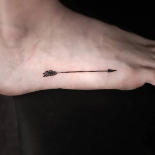 Small Blackwork Arrow Tattoo on Women Foot by @romano_tattooist