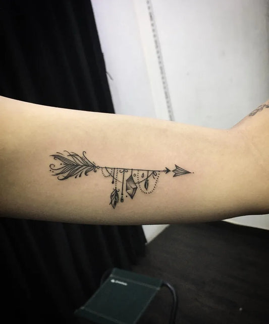 Small Blackwork Arrow and Feathers Tattoo on Women Forearm by @kaptaan_tattoo