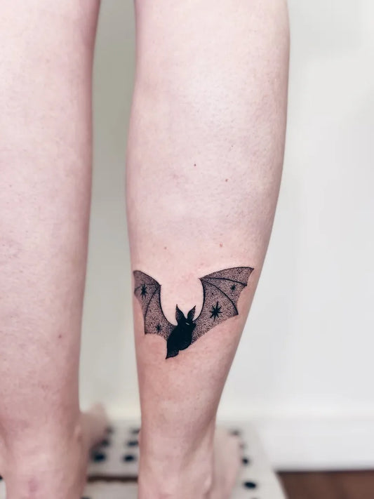 Small Blackwork Bat Tattoo on Women Leg by @flaviamar.co