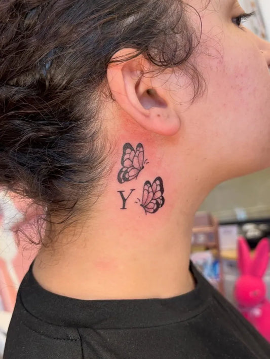 Small Blackwork Butterflies and Letter Tattoo on Women Behind the Ear by @maddie.stabs