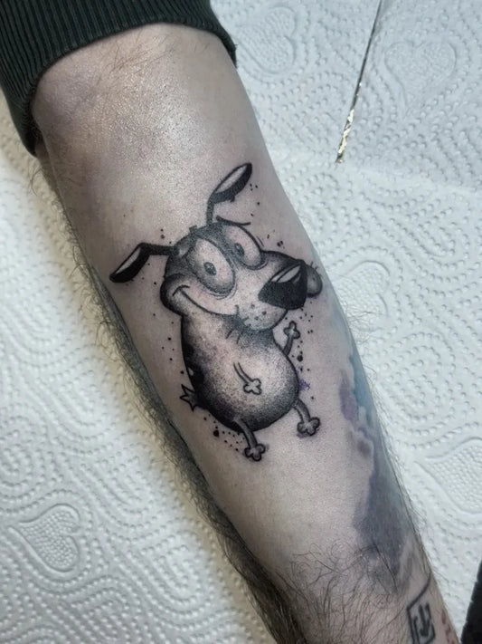 Small Blackwork Cartoon Dog Tattoo on Men Arm by @foxkitti.tattoo