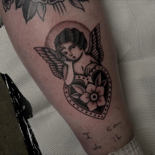 Small Blackwork Cherub Heart Tattoo on Women Arm by @nitrobolts.tattoo