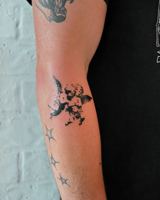 Small Blackwork Cherub and Stars Tattoo on Men Arm by @blancspacetattoo