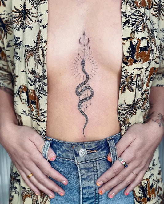 Small Blackwork Cosmic Snake on Women Sternum Tattoo by @nothingwildtattoo