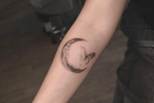 Small Blackwork Crescent Moon and Butterfly Tattoo on Women Arm by @e.bin_ink