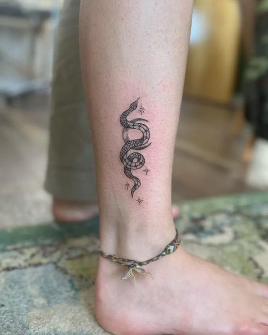 Small Blackwork Crescent Moon and Snake Tattoo on Women Ankle by @paintbrushtattoo